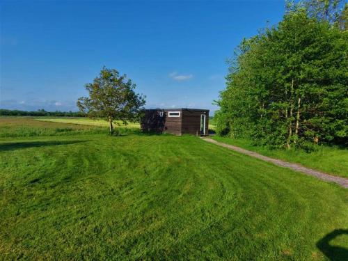 a small cabin in a field with a dirt road at Tiny house ''De Veenpolder'' in De Veenhoop