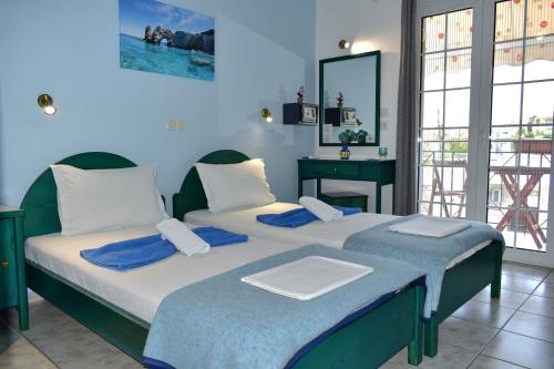 two beds in a room with blue walls at Pansion Pandora in Skiathos Town