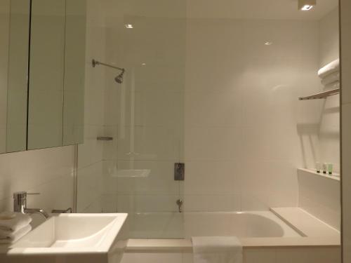 a white bathroom with a sink and a shower at Cosmopolitan Hotel and Apartments in Melbourne