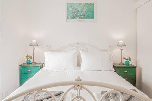 a bedroom with a white bed with two green night stands at Light and Central Apartment above Knead Bakery in Tetbury