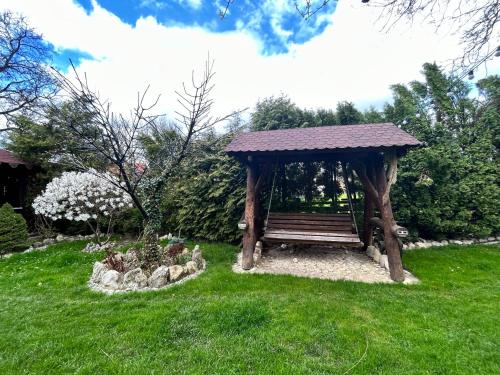 a wooden gazebo with a bench in the grass at Pensiunea Lorena in Bran