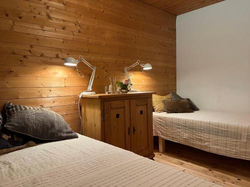 a bedroom with two beds and two lamps on a wooden wall at Schlechtbacher Sägmühle in Gschwend