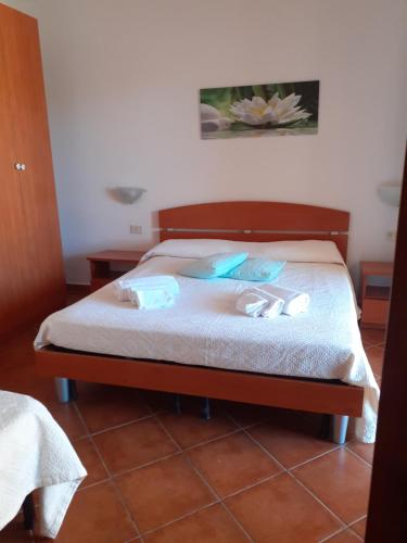 Una cama con sábanas blancas y toallas azules. en casa mirice in residence con piscina ,wifi,climatizzatore vicino al mare, en Aglientu