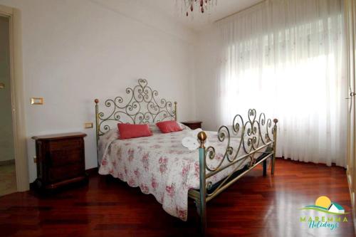 Maremma Holidays : Fiore Apartment في فولونيكا: غرفة نوم عليها سرير ومخدات حمراء