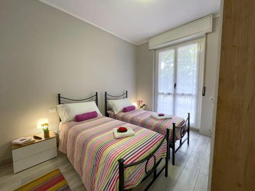 two beds in a small bedroom with a window at Bnbook Lattuada 3 camere da letto 2 bagni in Rho