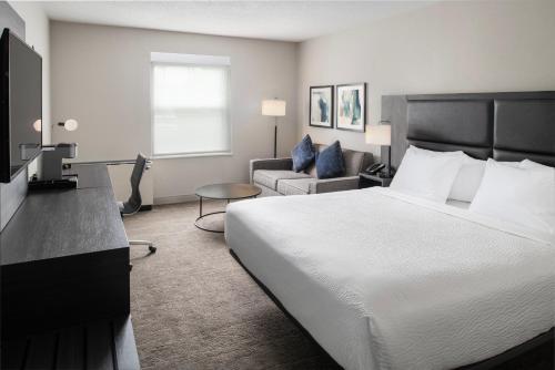 a hotel room with a bed and a couch at The Inn at Burlington, Trademark Collection by Wyndham in Burlington
