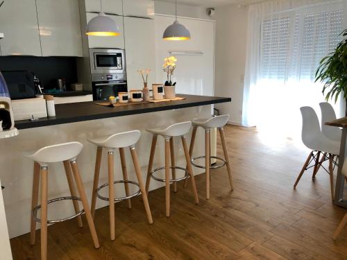a kitchen with white stools and a black counter top at Panorama Penthouse Apartment mit Klima und Whirlpool für bis zu 6 Personen in Frankenthal