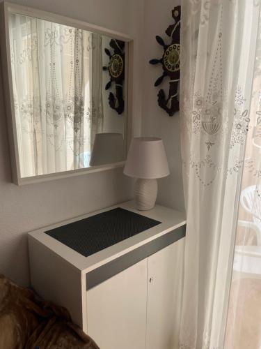 - une commode blanche avec un miroir et une lampe dans l'établissement Apartment Goya, à Torrevieja