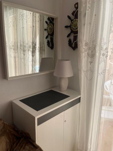 biała komoda z lustrem i lampą w obiekcie Apartment Goya w mieście Torrevieja