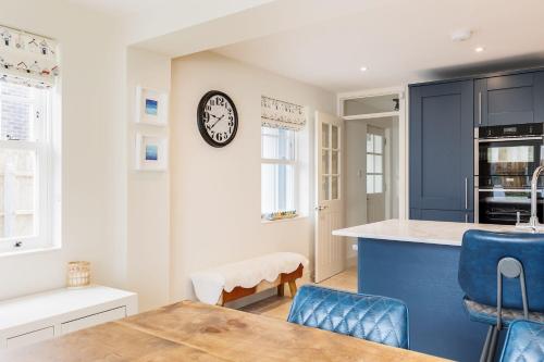 a kitchen with blue cabinets and a clock on the wall at Lobster Cottage in Poole