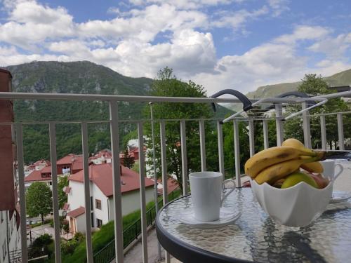 a bowl of bananas and a cup on a table on a balcony at Apartman Andjela in Pluzine