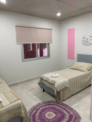 a bedroom with two beds and a window and a rug at Cómodo apartamento nuevo, zona aeropuerto! in Luque