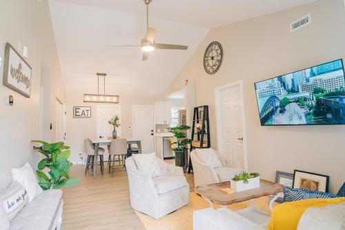 a living room with white furniture and a flat screen tv at City Retreat - 4 Bedroom Oasis with King & Private Yard near Downtown in Charlotte