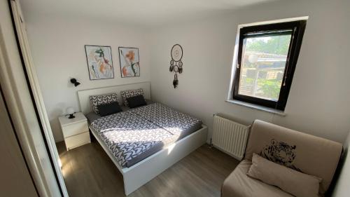 a bedroom with a bed and a window and a couch at Apartma Nomad in Novo Mesto