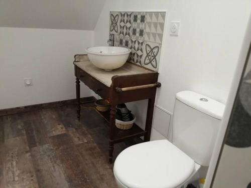a bathroom with a toilet and a bowl on a table at La romance de Laura in Arrest