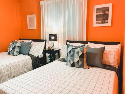 two beds in a room with orange walls at Casa del Arroyo 2-Bedroom Cottage Fireplace and BBQ in Jarabacoa