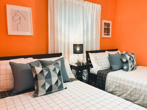 a bedroom with two beds and an orange wall at Casa del Arroyo 2-Bedroom Cottage Fireplace and BBQ in Jarabacoa