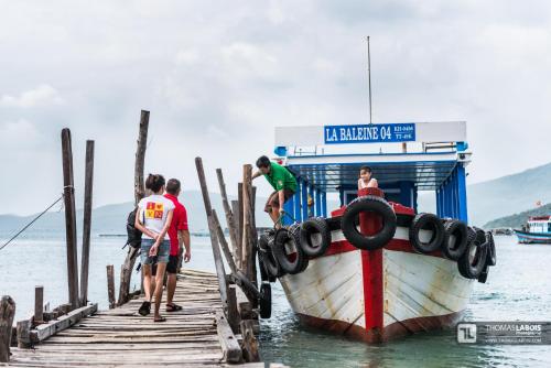a group of people standing on a dock next to a boat at Whale Island Resort in Dam Mon