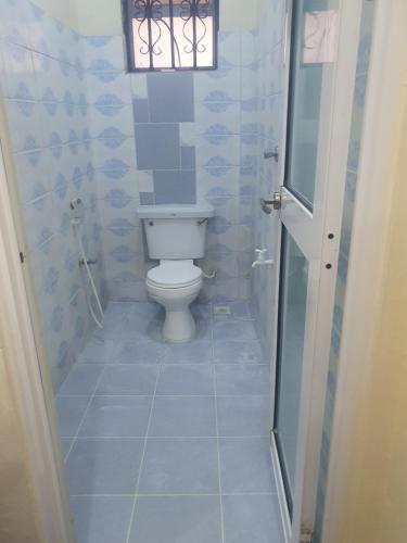 La salle de bains est pourvue de toilettes et d'une fenêtre. dans l'établissement Hellens homes, à Mombasa