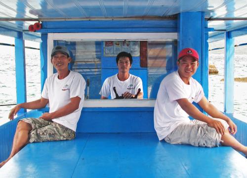 a group of three men sitting on a boat at Whale Island Resort in Dam Mon