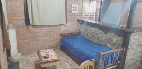 Habitación con cama azul y pared de ladrillo. en CABAÑA MELIPAL LOS MOLLES en Malargüe