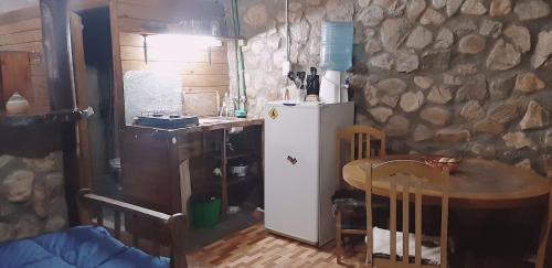 cocina con mesa pequeña y nevera blanca en CABAÑA MELIPAL LOS MOLLES en Malargüe