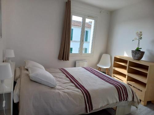 une chambre blanche avec un lit et une fenêtre dans l'établissement La Maison bleue des Mathes, aux Mathes