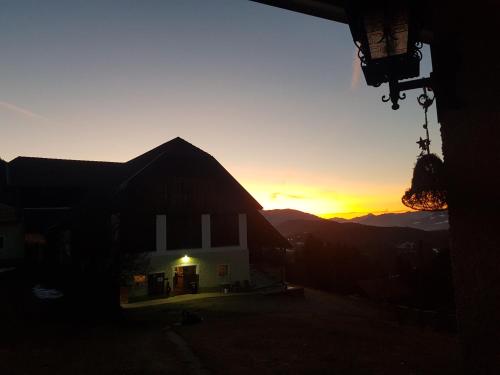 a sunset over a barn with the sun setting in the background at Bergbauernhof Rebernig in Lendorf