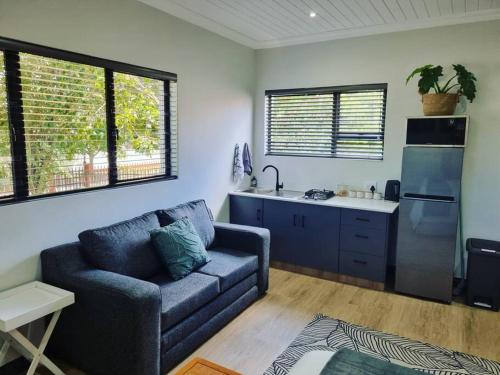 a living room with a couch and a kitchen at Palm On Rock - 1 bedroom,kitchenette & full bathroom. in Bloemfontein
