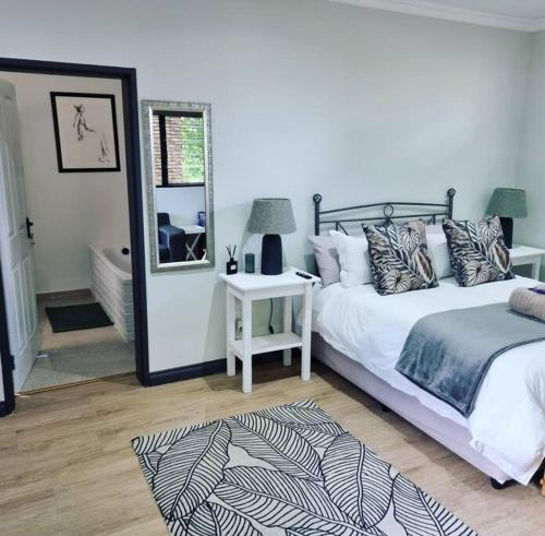 um quarto com uma cama branca e um espelho em Palm On Rock - 1 bedroom,kitchenette & full bathroom. em Bloemfontein