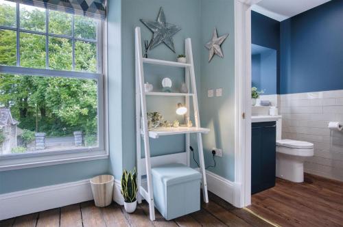a bathroom with blue walls and a white shelf at Hill House Country Estate - Princes Gate in Ludchurch