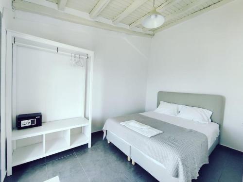 a white bedroom with a bed and a window at Emerald Suite Alonnisos in Patitiri