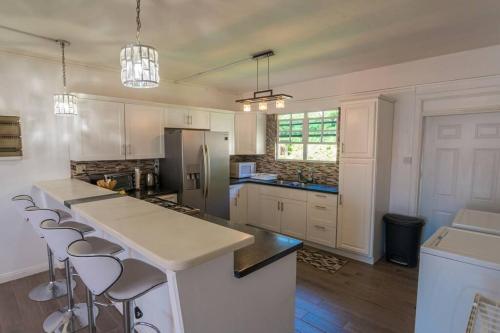 a kitchen with white cabinets and a large island with bar stools at VJ's Guesthouse Vacation Home, Jimmit, Dominica in Roseau