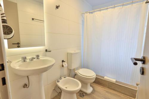 La salle de bains blanche est pourvue de toilettes et d'un lavabo. dans l'établissement Hotel Bariloche By Tierra Gaucha, à San Carlos de Bariloche
