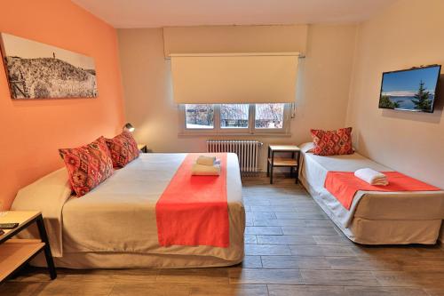 een slaapkamer met 2 bedden en een raam bij Hotel Bariloche By Tierra Gaucha in Bariloche