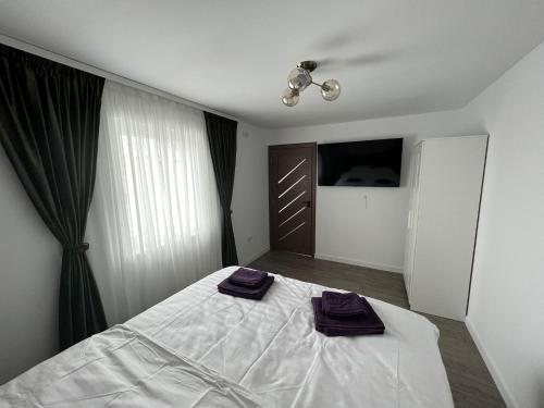 ein Schlafzimmer mit einem Bett mit lila Handtüchern darauf in der Unterkunft Kul House - Cazare in Băileşti