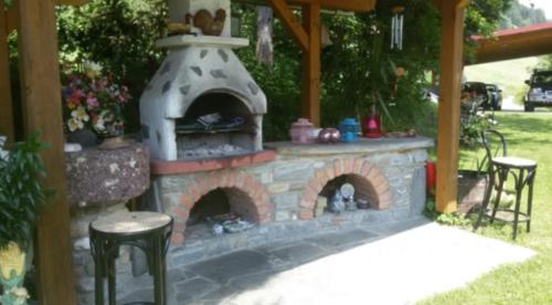 a stone fireplace in a yard with two stools at Bergbauernhof Rebernig in Lendorf