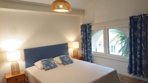 a bedroom with a bed with two lamps and a window at LES FLAMANTS in Portiragnes
