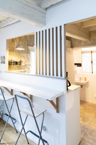 une cuisine avec un comptoir blanc et des chaises dans l'établissement Studios - Centre ville coeur historique, à Arles