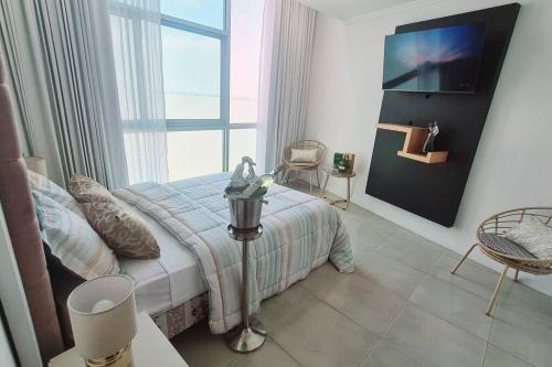 a bedroom with a bed and a tv on a wall at Suite Jacuzzi Vista Río junto Hotel Wyndham 1 in Guayaquil