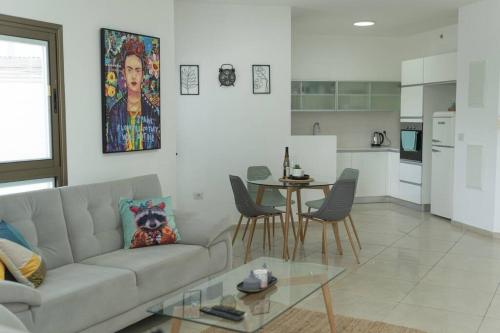 ein Wohnzimmer mit einem Sofa und einem Tisch sowie eine Küche in der Unterkunft Unique beach apartment in Rischon LeZion