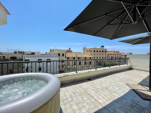 a hot tub on a balcony with an umbrella at NEWHOUSE ROOFTOP in Nettuno