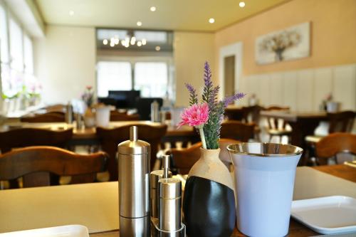 una mesa con dos jarrones con flores en un restaurante en Hotel Imperial en Krefeld