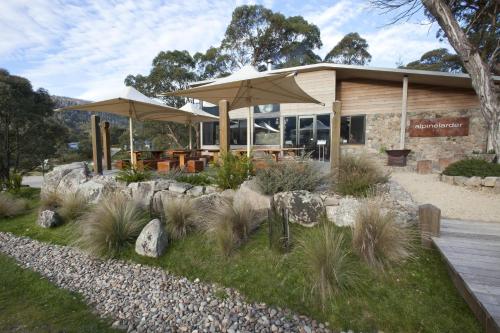 a restaurant with tables and umbrellas in a garden at Oaks Lake Crackenback Resort in Crackenback