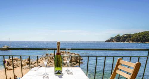a table with a wine bottle and glasses on a balcony at Apartamento exclusivo en primera línea de mar in Calella de Palafrugell