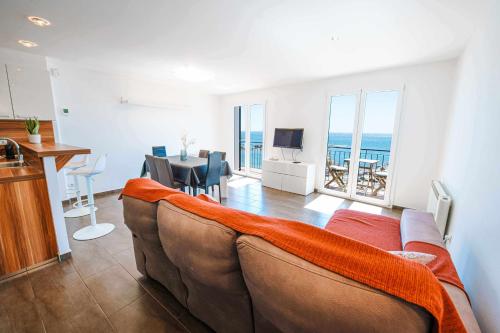 a living room with a couch and a dining room with the ocean at Apartamento exclusivo en primera línea de mar in Calella de Palafrugell