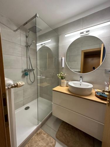 a bathroom with a shower and a sink and a mirror at Dachsteinblick apartment in Ramsau am Dachstein