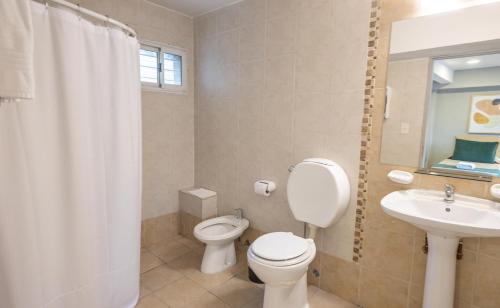 a white bathroom with a toilet and a sink at Hotel Plaza Bariloche in San Carlos de Bariloche