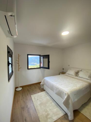 ein weißes Schlafzimmer mit einem Bett und einem Fenster in der Unterkunft Casa Rodrigues in Terras de Bouro