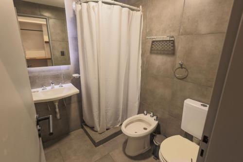 ein Badezimmer mit einem weißen Duschvorhang und einem WC in der Unterkunft HOTEL CONCEPT BARILOCHE in San Carlos de Bariloche
